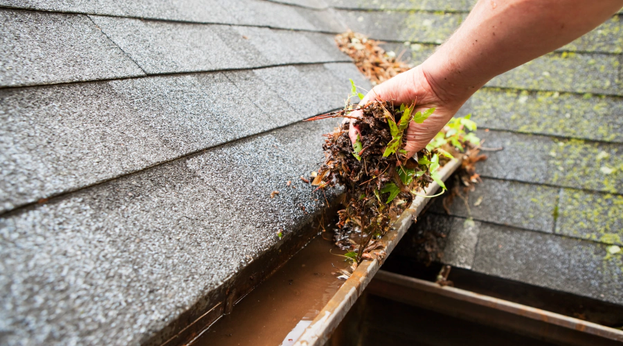 worker cleaning a gutter of a house